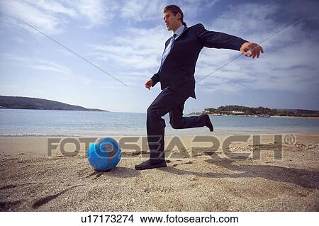 Picture - Businessman on beach with globe beach ball. Fotosearch