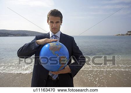 Stock Image - Businessman on beach with globe. Fotosearch