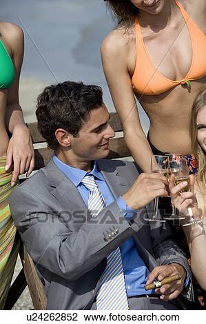 Stock Image - Businessman on beach with three women. Fotosearch