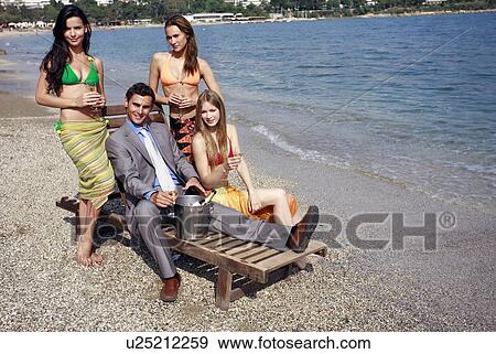 Stock Photo - Businessman on beach with three women. Fotosearch