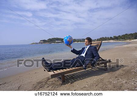 Businessman on chaise lounge with globe View Large Photo Image Picture - Businessman on chaise lounge with globe. Fotosearch