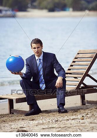 Stock Photography - Businessman on chaise lounge with globe. Fotosearch