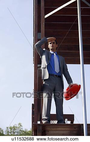 Stock Photo - Businessman on life guard stand with life preserver. Fotosearch