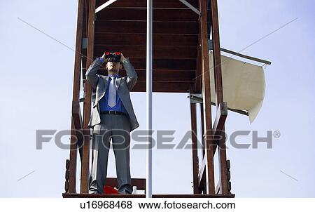 Stock Photo - Businessman on life guard stand with binoculars. Fotosearch