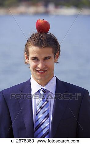Stock Image - Businessman with apple balanced on his head. Fotosearch