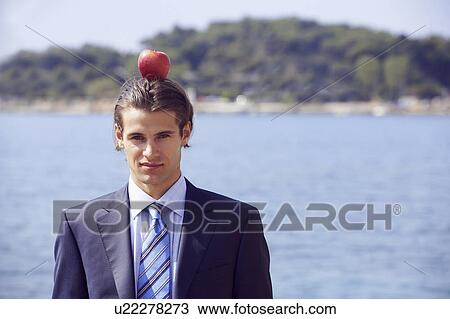 Stock Image - Businessman with apple balanced on his head. Fotosearch