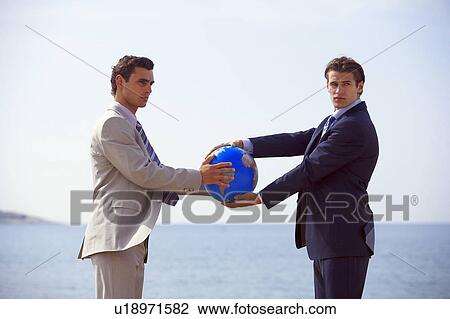 Businessmen on beach holding globe View Large Photo Image Stock Image - Businessmen on beach holding globe. Fotosearch
