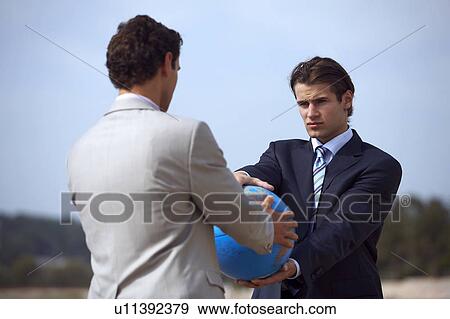 Businessmen on beach holding globe View Large Photo Image Stock Photo - Businessmen on beach holding globe. Fotosearch