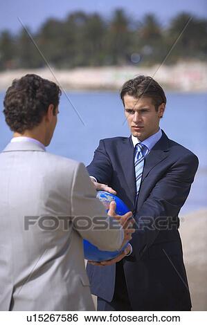 Businessmen on beach holding globe View Large Photo Image Stock Photograph - Businessmen on beach holding globe. Fotosearch