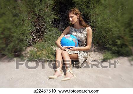 Stock Image - Businesswoman on beach with globe. Fotosearch