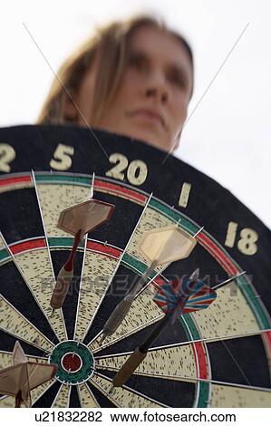 Stock Image - Closeup of woman holding dartboard. Fotosearch