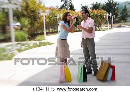 Couple with shopping bags, man offering roses View Large Photo Image Stock Photography - Couple with shopping bags, man offering roses. Fotosearch