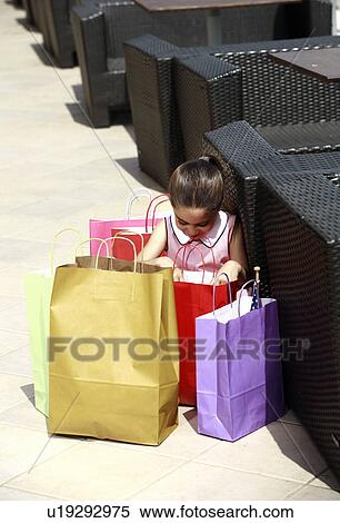 Stock Photography - Girl looking in shopping bags. Fotosearch
