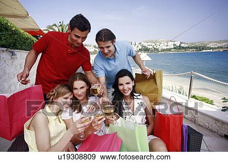 Stock Photo - Group of friends with shopping bags posing. Fotosearch