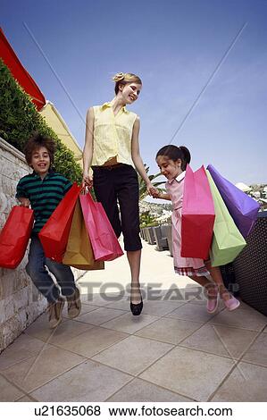 Mother and two children jumping with shopping bags View Large Photo Image Stock Photo - Mother and two children jumping with shopping bags. Fotosearch