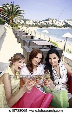 Stock Photography - Three women with shopping bags and wine posing. Fotosearch