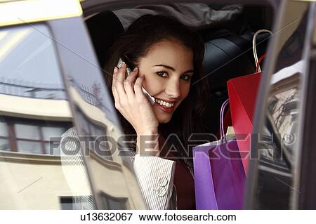 Woman on the cell phone with shopping bags in a taxi View Large Photo Image Stock Photo - Woman on the cell phone with shopping bags in a taxi. Fotosearch
