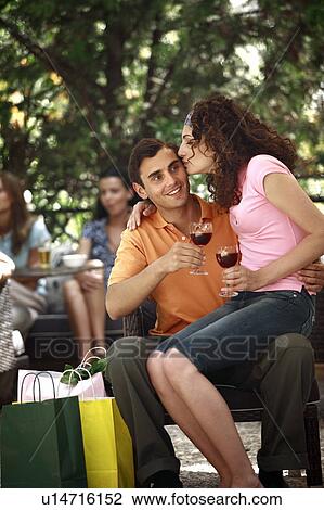 Stock Image - Woman sitting on man's lap with shopping bags in cafe. Fotosearch