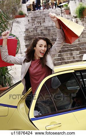 Woman with shopping bags getting out of a taxi View Large Photo Image Picture - Woman with shopping bags getting out of a taxi. Fotosearch
