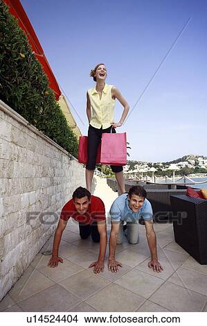 Woman with shopping bags standing on men View Large Photo Image Picture - Woman with shopping bags standing on men. Fotosearch