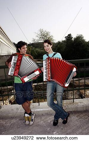 Stock Image - Couple at archaeological site playing accordion. Fotosearch