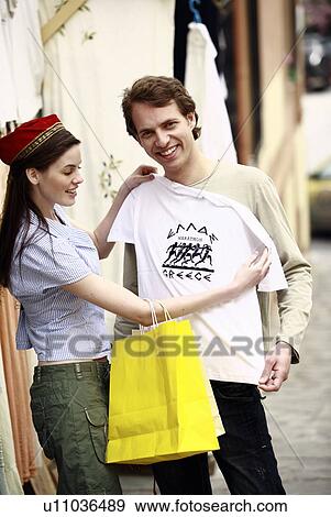 Stock Photo - Couple shopping for a Greece tee shirt. Fotosearch