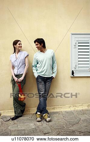 Stock Image - Man and woman at a wall with a picnic lunch. Fotosearch