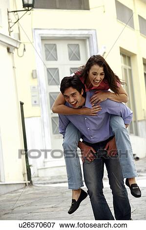 Stock Photo - Man giving woman a piggy back ride. Fotosearch