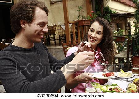 Picture - Man serving woman at table. Fotosearch
