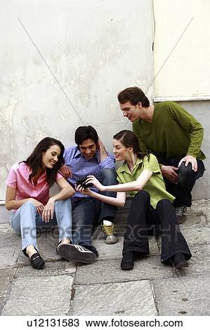 Stock Image - Two couples looking at digital camera. Fotosearch