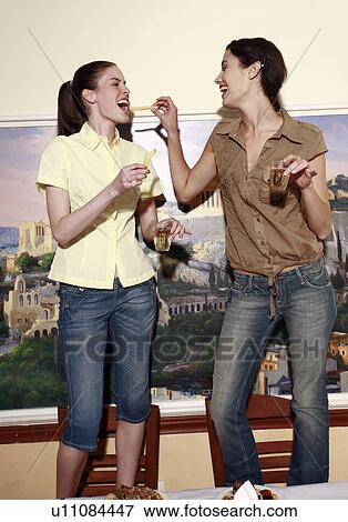 Two women on chairs with wine and fries View Large Photo Image Stock Photo - Two women on chairs with wine and fries. Fotosearch