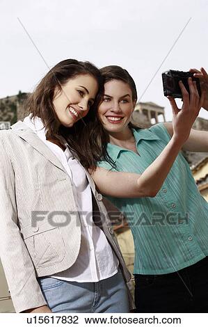 Stock Image - Two women photographing themselves. Fotosearch