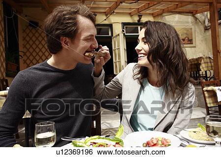 Stock Photograph - Woman feeding man a lamb chop. Fotosearch