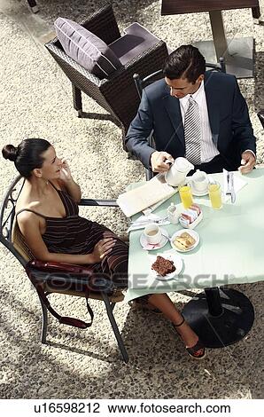 Business couple in garden cafe drinking orange juice View Large Photo Image Stock Image - Business couple in garden cafe drinking orange juice. Fotosearch