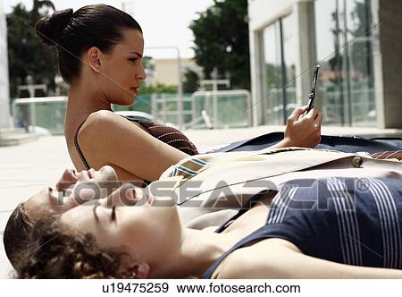 Business people lying on the ground, woman making phone call View Large Photo Image Stock Photo - Business people lying on the ground, woman making phone call. Fotosearch