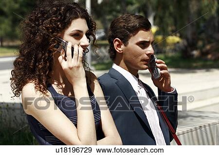 Stock Photo - Businessman and businesswoman on cell phones. Fotosearch