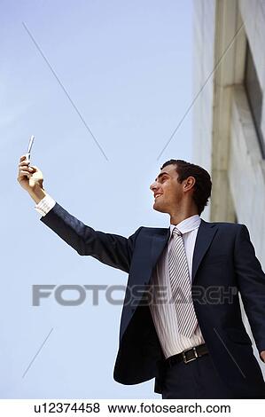 Businessman holding cell phone to get a signal View Large Photo Image Stock Photo - Businessman holding cell phone to get a signal. Fotosearch