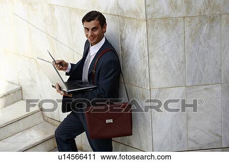 Businessman holding laptop and cell phone View Large Photo Image Stock Image - Businessman holding laptop and cell phone. Fotosearch