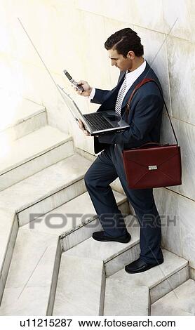Businessman holding laptop and cell phone View Large Photo Image Stock Photo - Businessman holding laptop and cell phone. Fotosearch