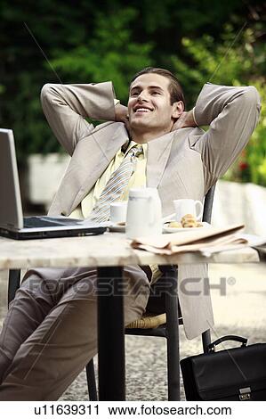 Stock Image - Businessman in garden cafe with laptop. Fotosearch