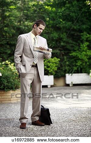 Stock Photography - Businessman in garden looking at watch. Fotosearch