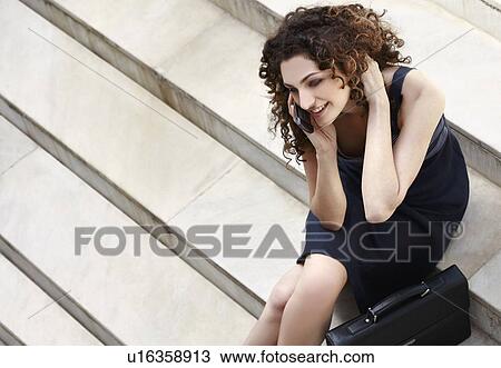 Businesswoman on cell phone sitting with briefcase View Large Photo Image Stock Image - Businesswoman on cell phone sitting with briefcase. Fotosearch