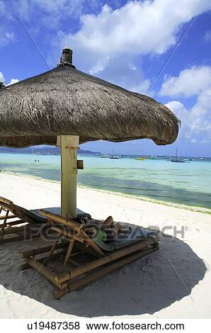 A person enjoying the cool on beach chairs under the sunshade View Large Photo Image Stock Photo - A person enjoying the cool on beach chairs under the sunshade. Fotosearch