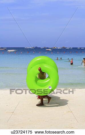 People holding inflatable ring walking on the beach View Large Photo Image Stock Photography - People holding inflatable ring walking on the beach. Fotosearch