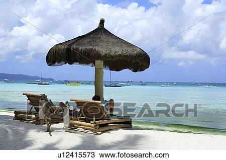 Stock Image - People relaxing on beach chair under the sunshade. Fotosearch