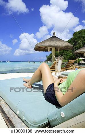 Young woman relaxing on beach chair View Large Photo Image Stock Photo - Young woman relaxing on beach chair. Fotosearch