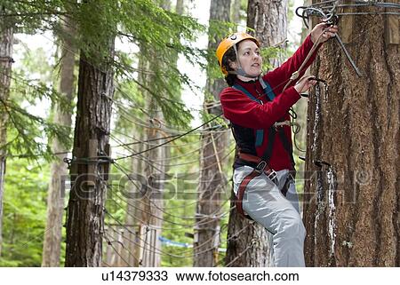 Stock Image - A woman works her way through a high ropes course at the Strathcona Park Lodge, BC. Fotosearch