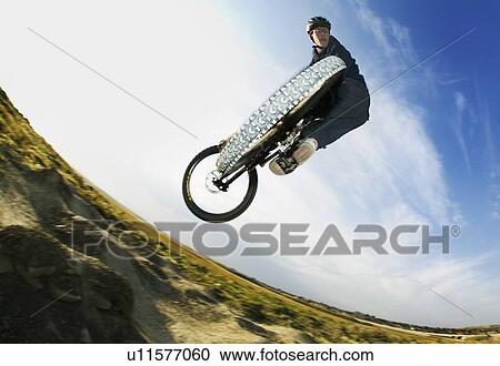 Stock Image - Fish eye low angle view of mountain biker jumping; Canada, Alberta, Calgary. Fotosearch