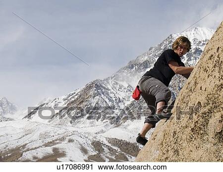 Man (20-25) climbing a rock face with a snow-capped mountain in the background, Bishop, California View Large Photo Image Stock Image - Man (20-25) climbing a rock face with a snow-capped mountain in the background, Bishop, California. Fotosearch