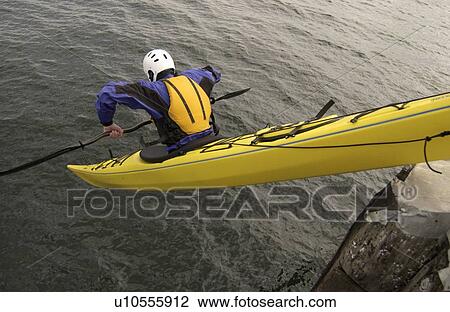 Stock Image - Man (30-35) dropping off a pier in an ocean kayak, Sidney, BC, Canada. Fotosearch